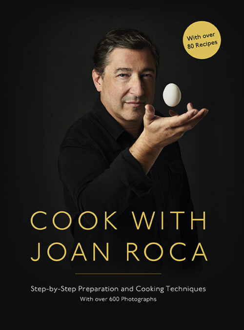 Joan Roca holding an egg wearing a black shirt with a black background