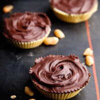 chocolate peanut tartlets in yellow cupcake cases on a black board.